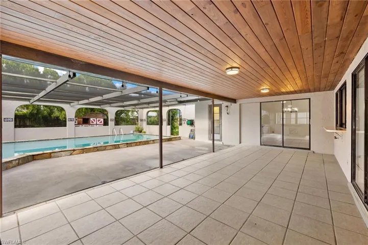 View of pool featuring a patio area and glass enclosure