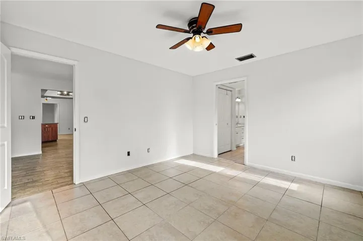 Tiled spare room featuring ceiling fan
