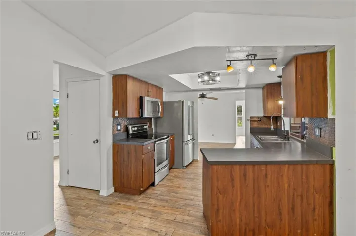 Kitchen featuring track lighting, stainless steel appliances, sink, kitchen peninsula, and backsplash