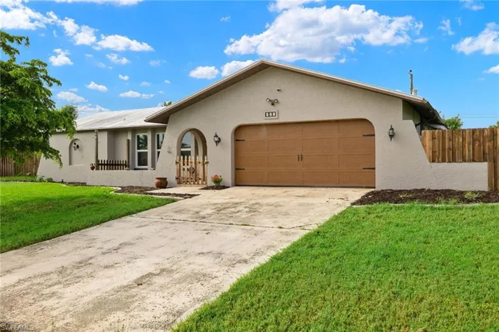 Ranch-style home featuring a garage and a front lawn