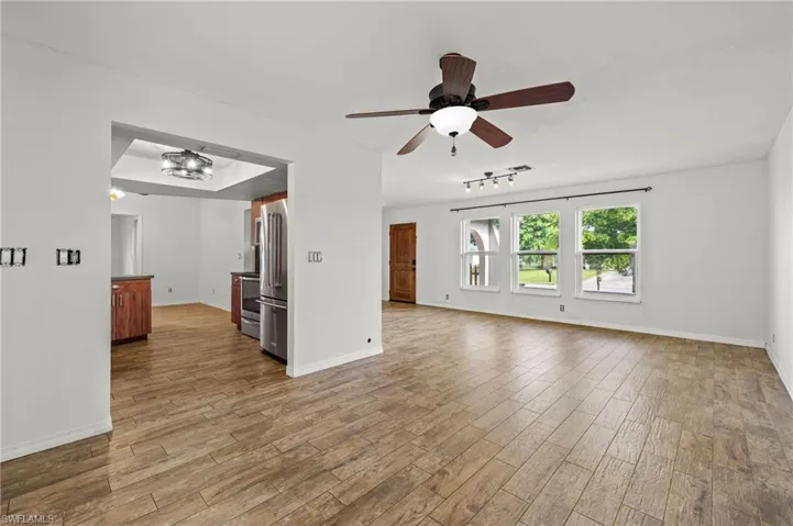 Empty room with rail lighting, hardwood / wood-style flooring, and ceiling fan
