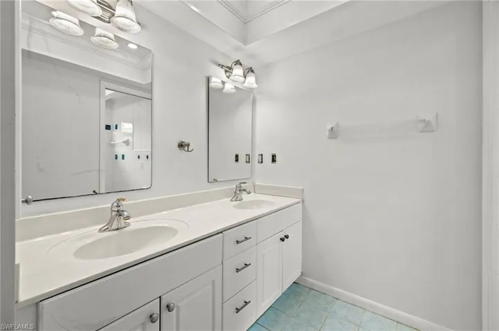 Bathroom featuring double vanity, tile patterned floors, and crown molding