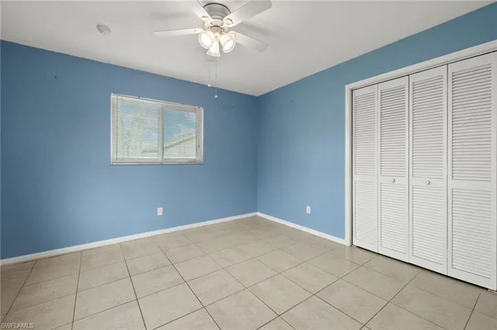 Unfurnished bedroom with ceiling fan, light tile patterned floors, and a closet