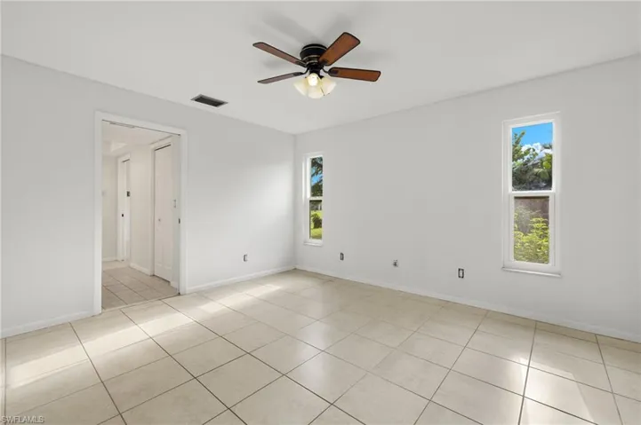 Empty room with light tile patterned floors and ceiling fan