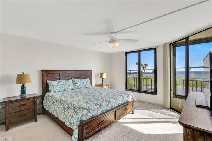 Carpeted bedroom with a water view and ceiling fan