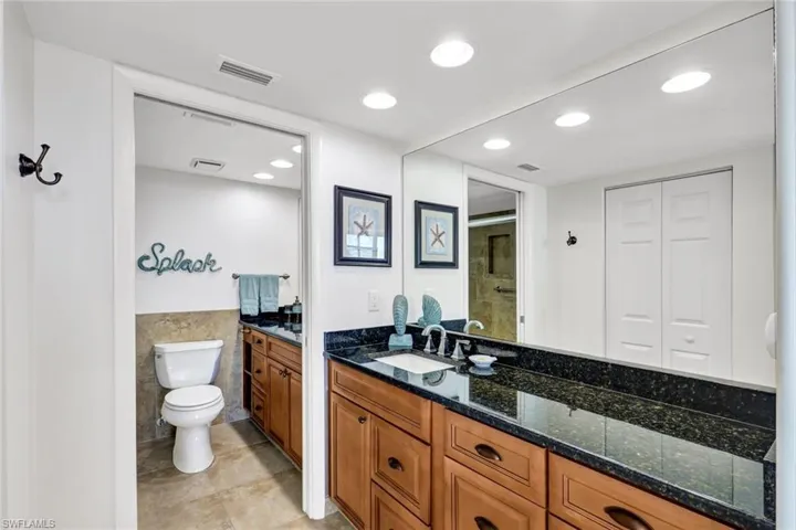 Bathroom with tile patterned flooring, tile walls, toilet, and vanity