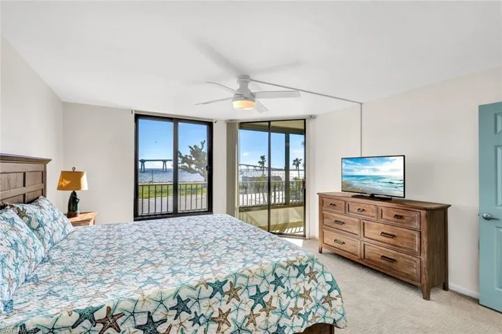 Bedroom featuring light carpet, a wall of windows, ceiling fan, and access to exterior