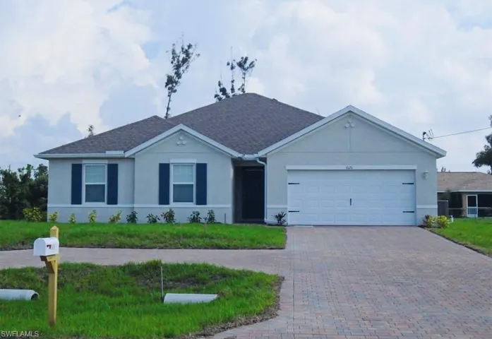 Single story home with decorative driveway, a front yard, an attached garage, and stucco siding