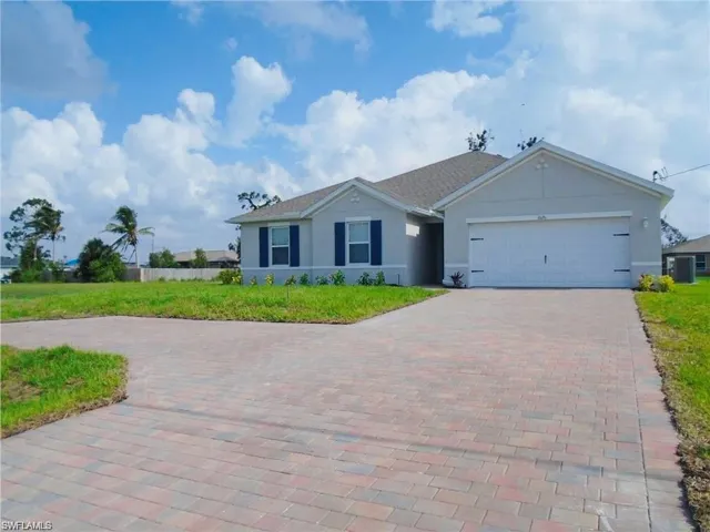 Ranch-style home with cooling unit, stucco siding, an attached garage, and decorative driveway