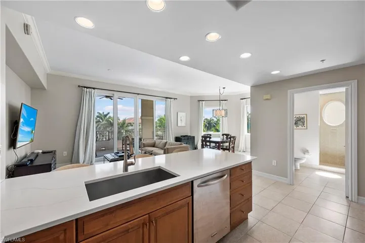 Kitchen featuring stainless steel dishwasher, brown cabinets, open floor plan, recessed lighting, and light countertops