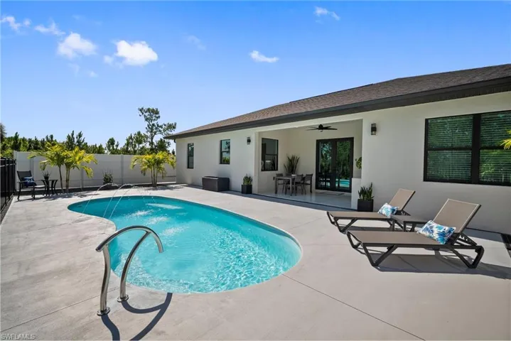 View of pool with pool water feature, a patio area, and ceiling fan