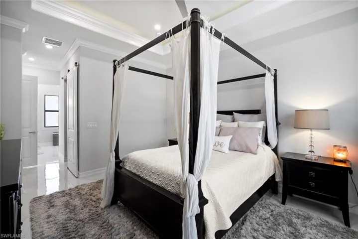 Tiled bedroom with a barn door and crown molding