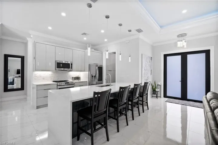 Kitchen featuring crown molding, sink, hanging light fixtures, and stainless steel appliances