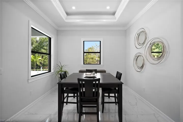 Tiled dining area featuring plenty of natural light, a tray ceiling, and crown molding