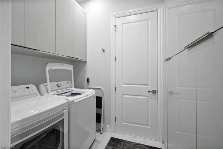 Laundry room featuring washer and dryer, cabinets, and light tile flooring
