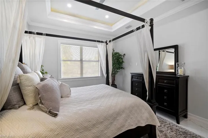 Bedroom featuring crown molding, tile floors, and a raised ceiling