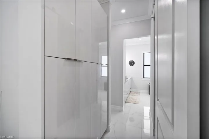 Hallway with light tile flooring and crown molding