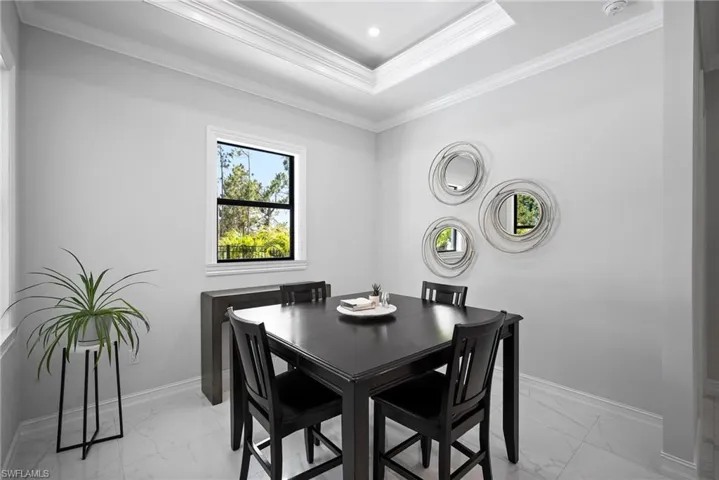 Tiled dining space with a raised ceiling and crown molding