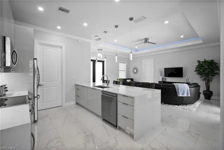 Kitchen featuring appliances with stainless steel finishes, a tray ceiling, pendant lighting, sink, and light tile floors