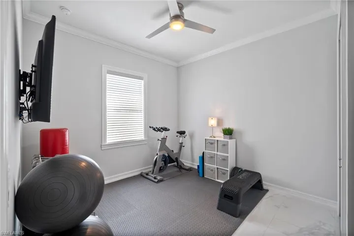 Workout area featuring tile floors, ceiling fan, and crown molding
