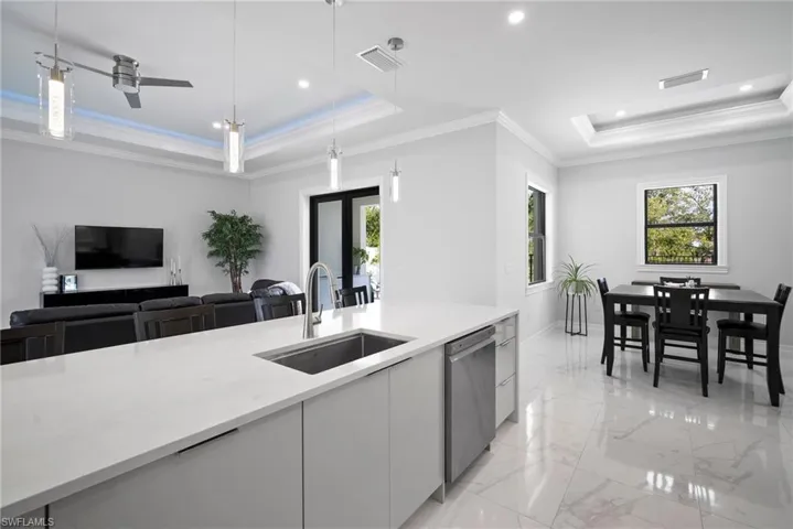 Kitchen with ceiling fan, a tray ceiling, decorative light fixtures, sink, and dishwasher