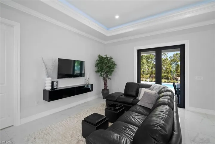 Tiled living room featuring a raised ceiling and crown molding