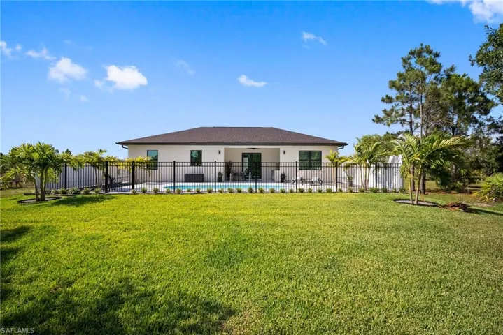 Rear view of house featuring a fenced in pool and a lawn