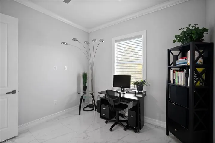 Office space with ornamental molding and light tile flooring