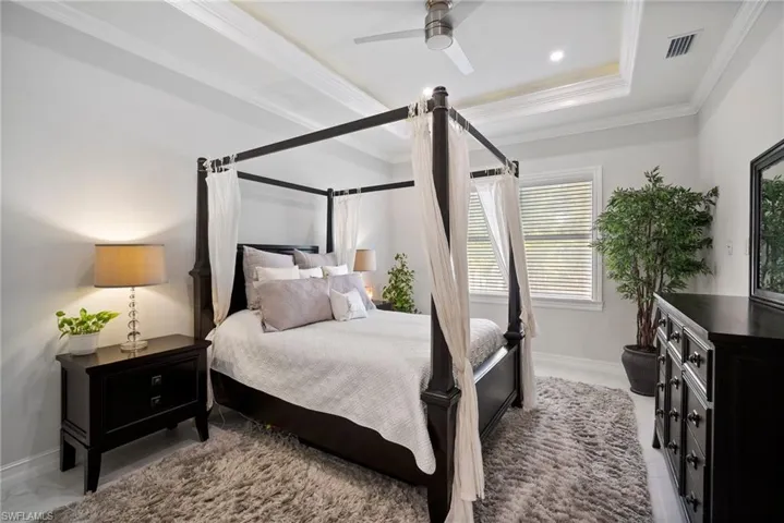 Bedroom featuring ceiling fan, a raised ceiling, and crown molding