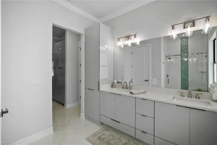 Bathroom with a shower, tile flooring, crown molding, and double vanity
