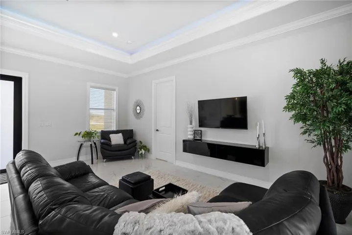 Tiled living room featuring a tray ceiling and crown molding