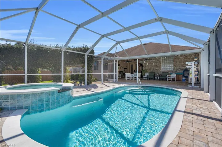 Combined pool / hot tub with a sunroom, a lanai, and a patio