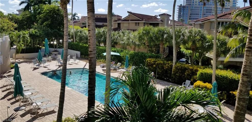 Sund drenched pool area with some shade available, lots of chairs and umbrellas plus a gated walkway to the beachfront across the manicured grounds.