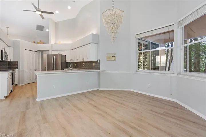 Kitchen with white cabinetry, ceiling fan, appliances with stainless steel finishes, a high ceiling, and light wood-style flooring