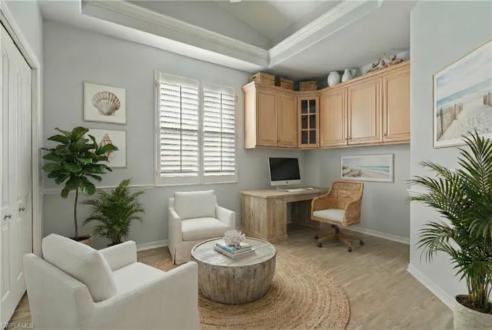 Home office featuring vaulted ceiling, built in desk, and light wood-style floors