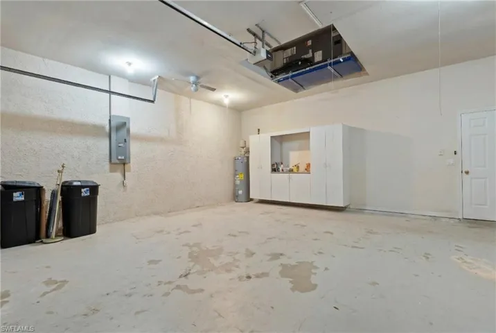 Garage with electric panel, electric water heater, and ceiling fan