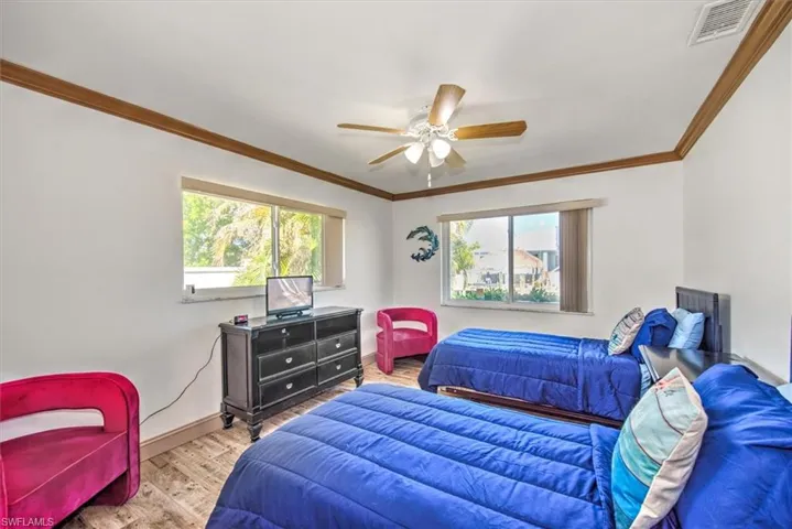 Bedroom with wood finished floors, crown molding, and ceiling fan