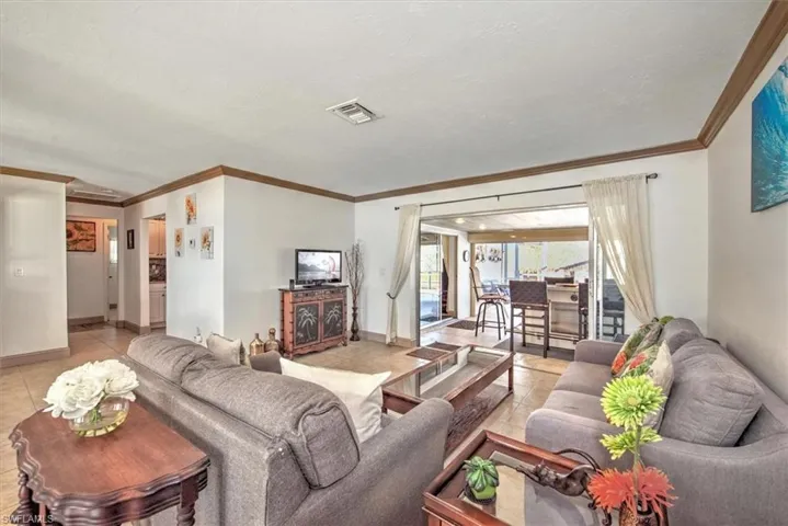 Living area featuring light tile patterned floors and crown molding