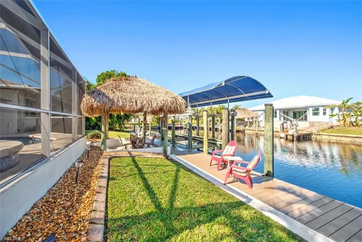 Dock featuring glass enclosure, boat lift, a water view, a yard, and a gazebo