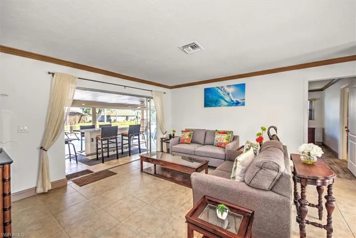 Living room with light tile patterned floors and crown molding
