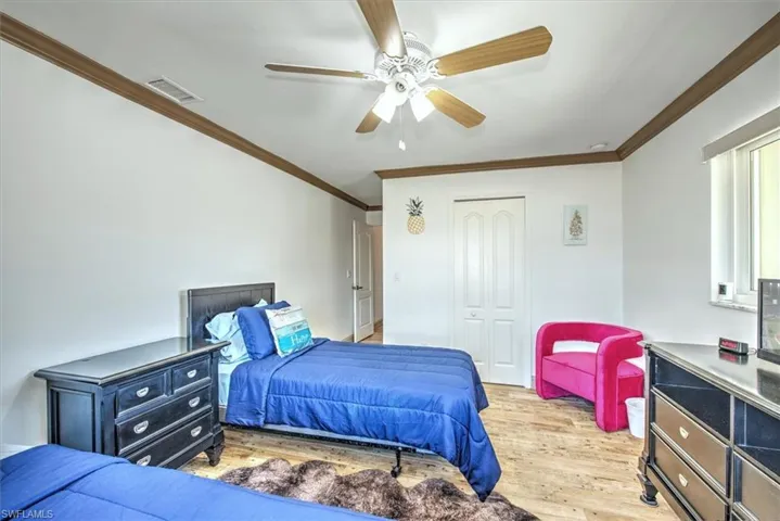 Bedroom with ornamental molding, light wood finished floors, a ceiling fan, and a closet