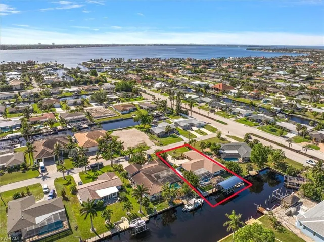 Aerial view of residential area with property boundaries highlighted and a nearby body of water