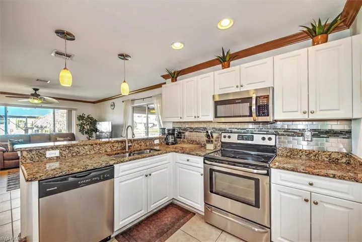 Kitchen with stainless steel appliances, white cabinets, a peninsula, ornamental molding, and recessed lighting