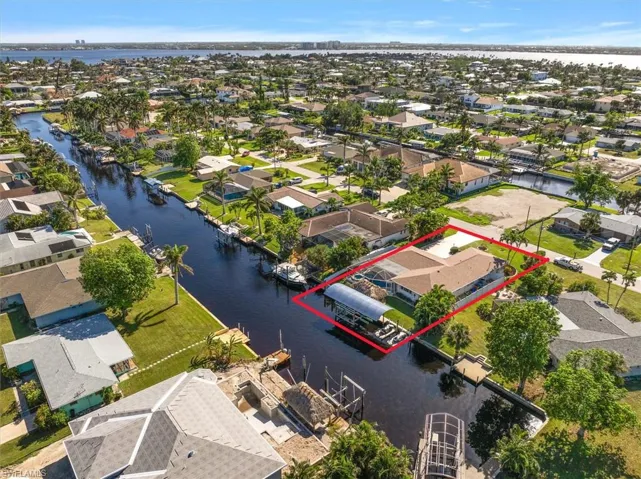 Aerial perspective of suburban area featuring property parcel outlined and a nearby body of water