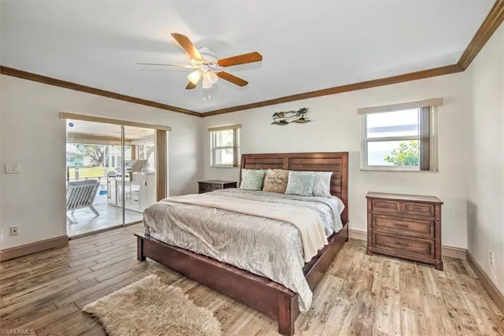 Bedroom featuring access to outside, multiple windows, crown molding, and a ceiling fan