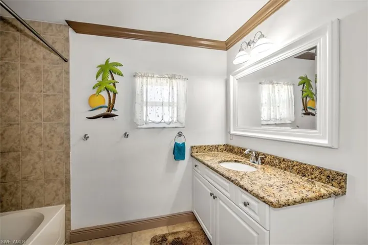 Full bathroom featuring vanity, light tile patterned flooring, and washtub / shower combination