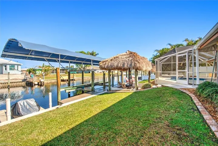 Dock area featuring a sunroom, boat lift, a lanai, a water view, and a swimming pool