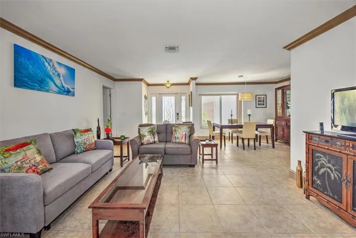 Living area with crown molding and light tile patterned flooring