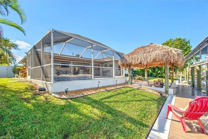 Rear view of property with glass enclosure, a patio area, and a sunroom