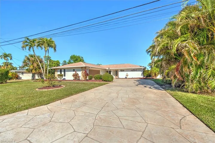 Ranch-style house featuring concrete driveway, a front lawn, and a garage